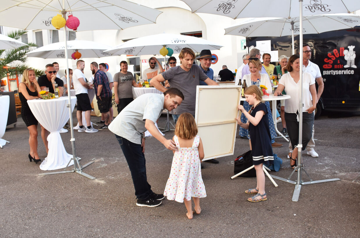 Kinder zeigen ihr gemaltes Bild den stolzen Vätern. Sommerfest 2018 stolze Väter